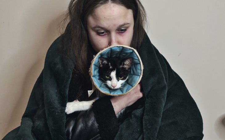 Dziewczyna z kotem w kocu, przytulająca się.