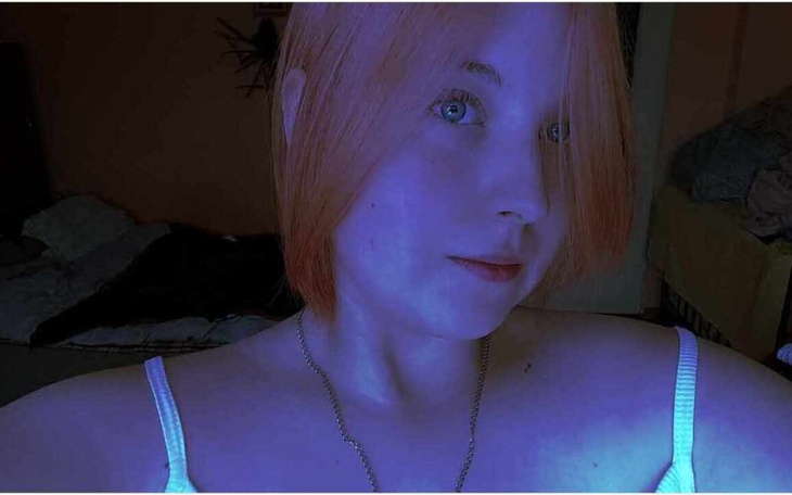 Portret osoby z krótkimi, pomarańczowymi włosami w niebieskim świetle.