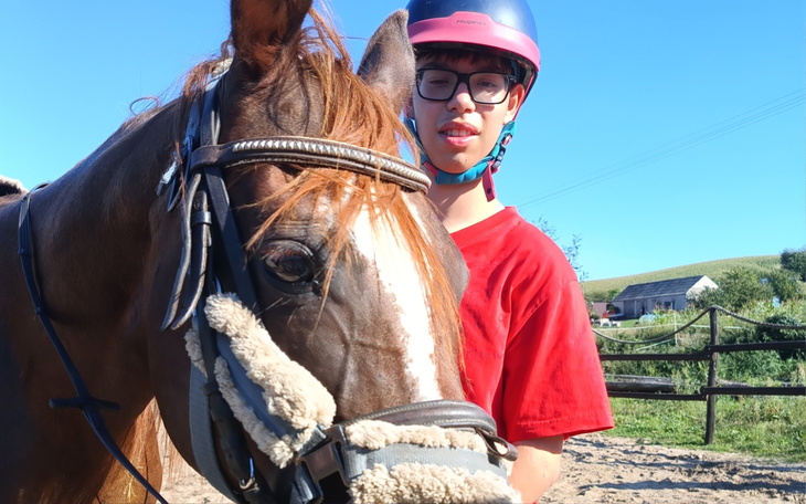 Chłopiec na koniu, uśmiechający się w kasku.