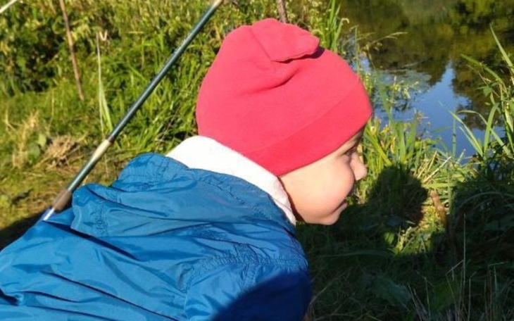 Chłopiec w czerwonej czapce obserwuje wodę.