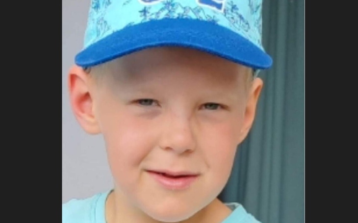 Chłopiec w niebieskiej czapce, uśmiechający się do kamery.