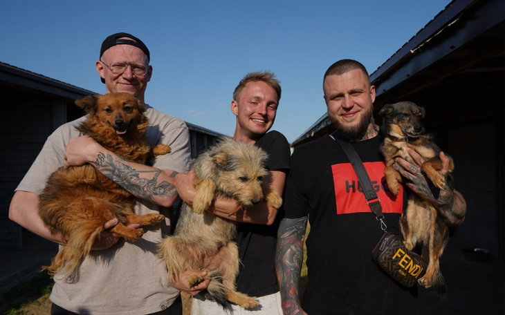 Czterej mężczyźni trzymają psy w ramionach, uśmiechając się do kamery.