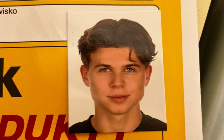 Zdjęcie młodego mężczyzny z uśmiechem, na tle żółtej tablicy.