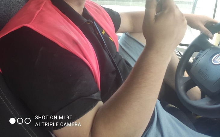 Kierowca w różowej kamizelce, trzymający telefon.