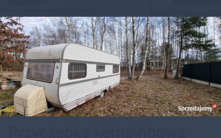 Przyczepa kempingowa zaparkowana w lesie.
