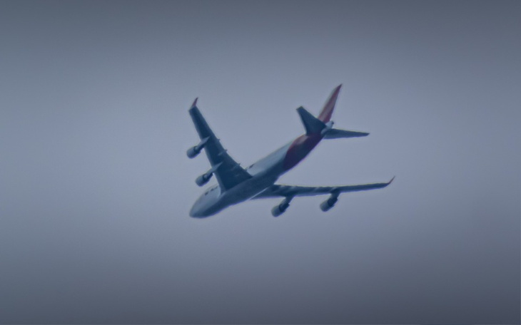 Samolot w locie, widoczny na szarym niebie.