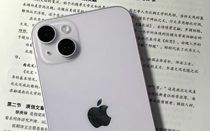 Smartfon Apple iPhone 13 leżący na kartkach tekstu.