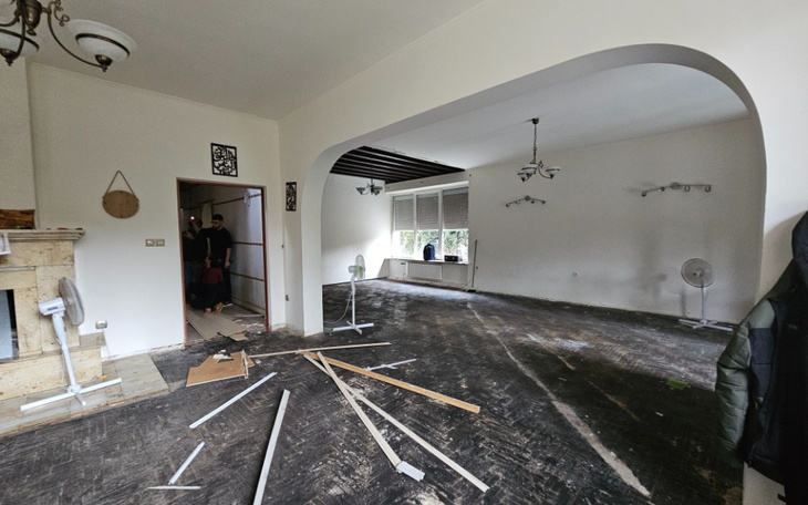 Pusty pokój z rozrzuconymi materiałami budowlanymi i widokiem na drugą część mieszkania.