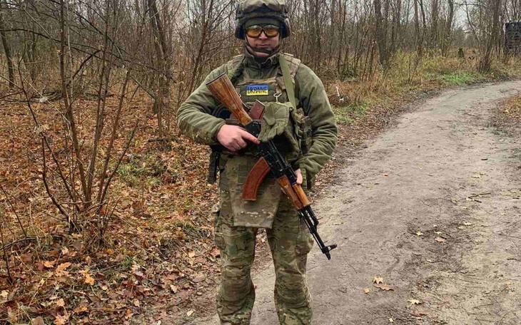 Mężczyzna w mundurze wojskowym, trzymający karabin w lesie.