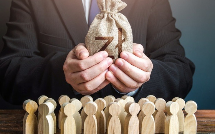 Mężczyzna trzymający worek z pieniędzmi przed grupą ludzi.