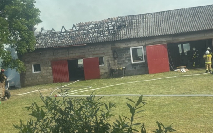 Zniszczony budynek po pożarze, strażacy w akcji.