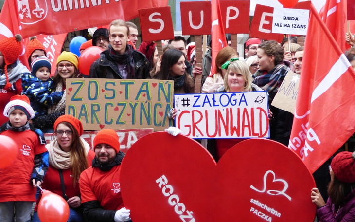 Ludzie na demonstracji, trzymający transparenty i balony.