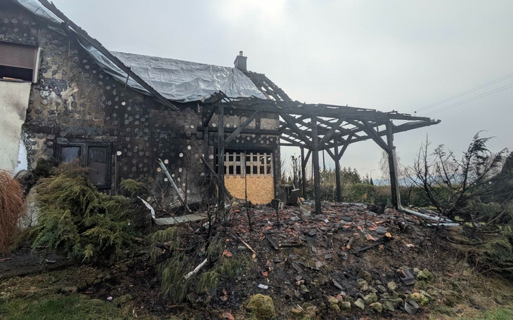 Zniszczony dom po pożarze, z uszkodzoną konstrukcją dachu.