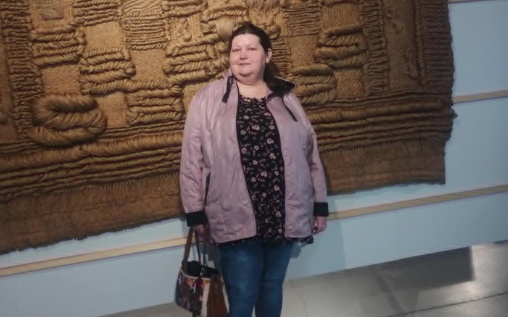 Kobieta pozująca przed tłem z tkaniny w muzeum.