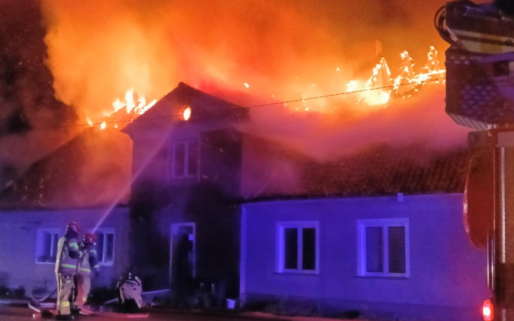 Pożar domu, strażacy walczą z ogniem w nocy.