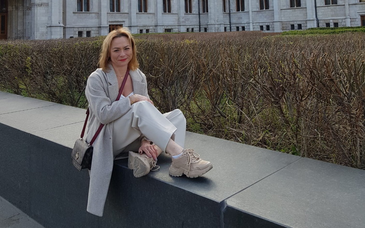 Kobieta siedząca na murku, w eleganckim stroju.