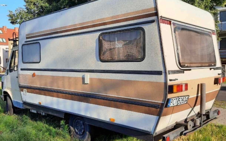 Stary kamper zaparkowany na trawie, z widocznymi oznakami zużycia.