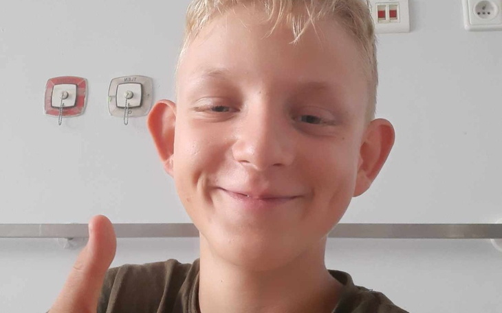 Chłopiec z uśmiechem, pokazujący kciuk w górę.