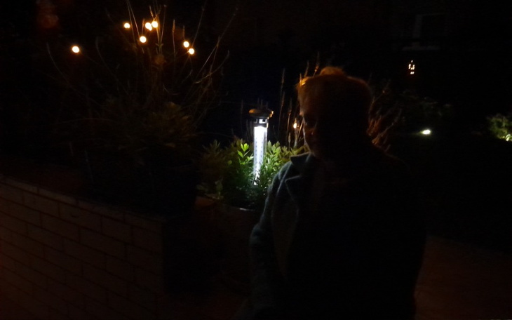 Osoba w cieniu, z lampą w tle, w nocy.