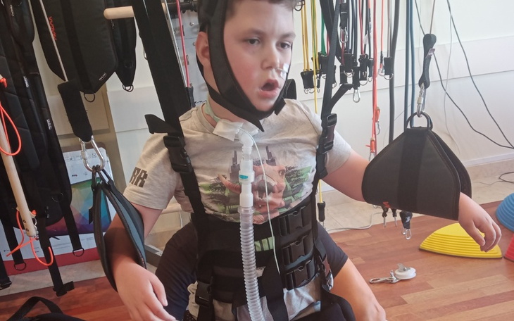 Chłopiec w specjalnym sprzęcie rehabilitacyjnym.
