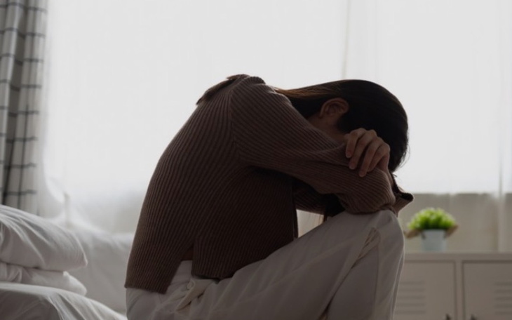 Osoba siedząca w smutnej pozycji, z głową w kolanach.