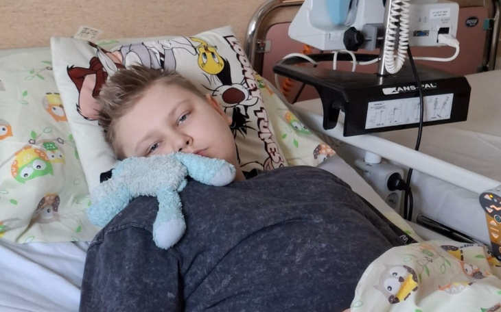 Chłopiec w szpitalnym łóżku, trzymający pluszowego kraba.