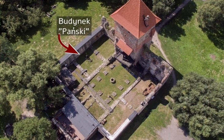 Widok z lotu ptaka na zamek z wieżą i ruinami.