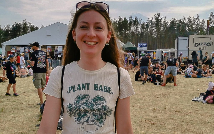 Uśmiechnięta dziewczyna na festiwalu, w tle tłum ludzi.