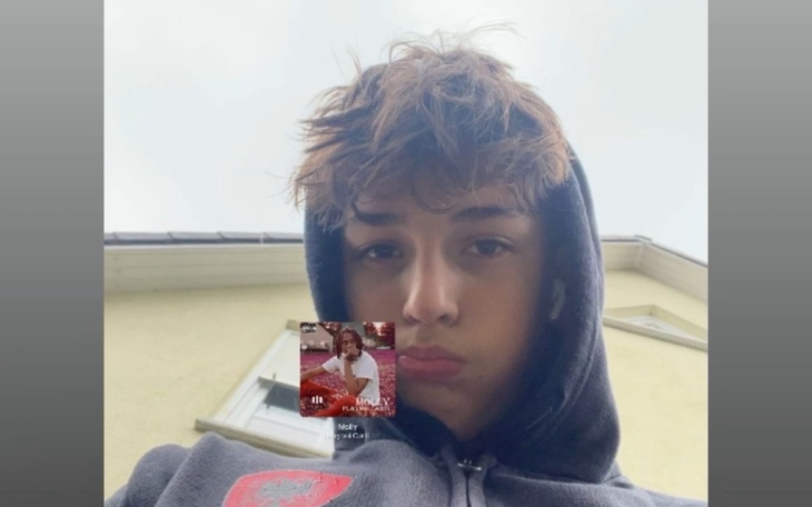 Chłopak w bluzie z kapturem, z nieco smutnym wyrazem twarzy.