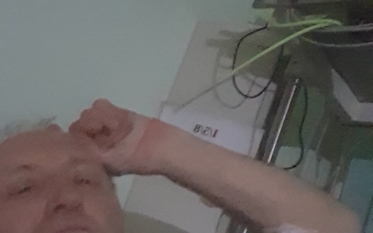 Mężczyzna w szpitalu, widoczna ręka i sprzęt medyczny.