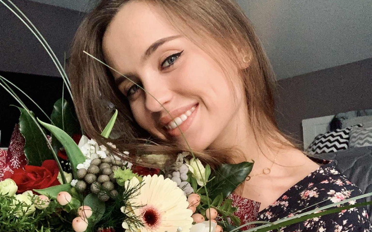 Uśmiechnięta kobieta z bukietem kwiatów w rękach.