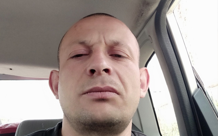 Mężczyzna w samochodzie, z poważnym wyrazem twarzy.