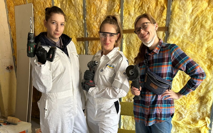 Trzy kobiety w kombinezonach, gotowe do pracy.