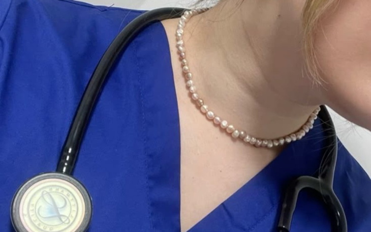 Kobieta w niebieskim uniformie medycznym z naszyjnikiem z pereł.