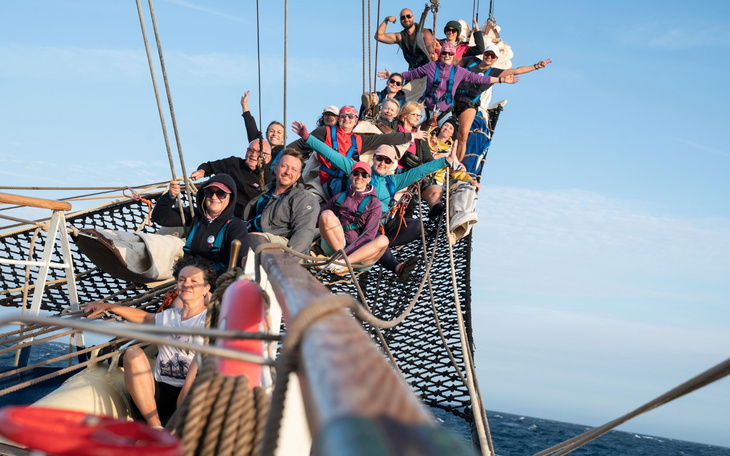 Grupa ludzi na pokładzie statku, cieszą się wspólnym czasem.