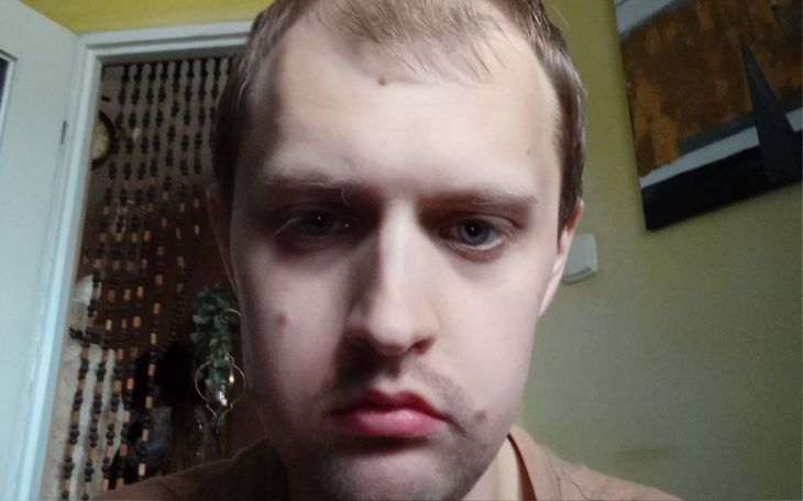 Mężczyzna z zamyśloną miną, siedzący w pokoju.