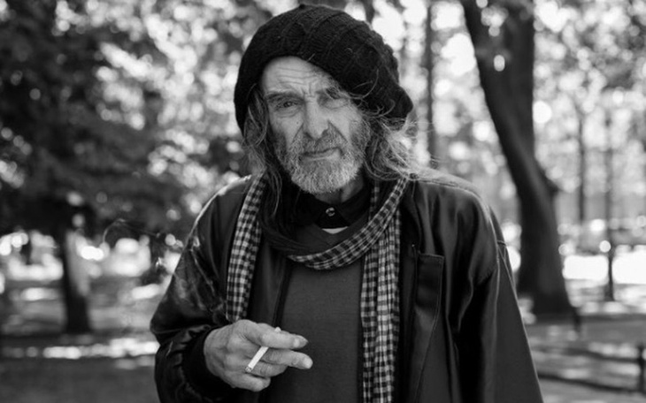 Człowiek w parku, palący papierosa, w stylu czarno-białym.