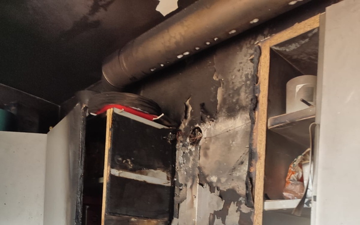 Zniszczona kuchnia po pożarze, z uszkodzonymi meblami.