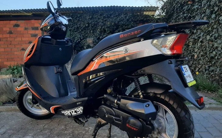 Skuter w kolorze czarnym z pomarańczowymi akcentami.