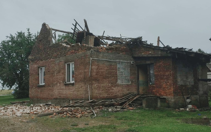 Zniszczony dom z uszkodzonym dachem i gruzem wokół.
