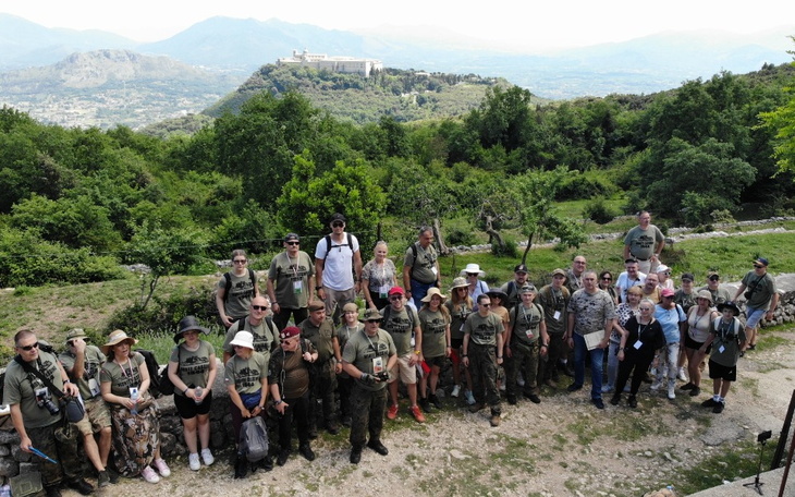 Grupa ludzi na szlaku górskim z widokiem na dolinę.