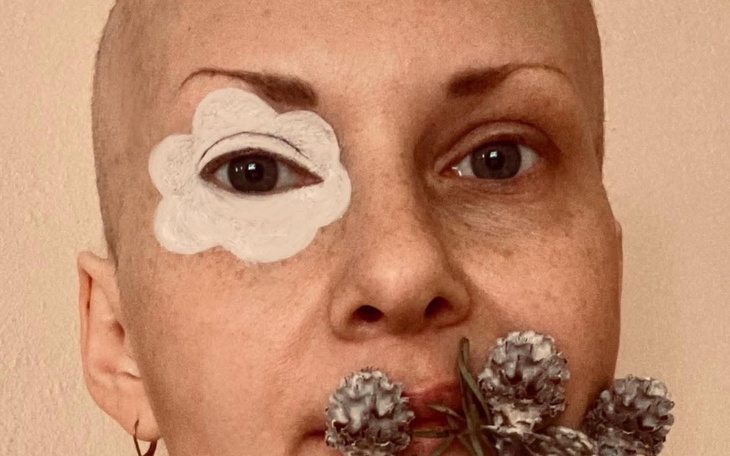 Kobieta z krótkimi włosami trzymająca kwiaty.