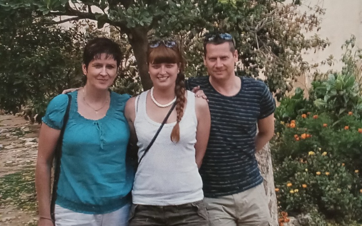 Trzy osoby pozujące na tle zieleni, uśmiechnięte i zrelaksowane.