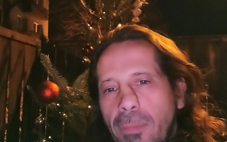 Mężczyzna z długimi włosami, selfie przy choince.