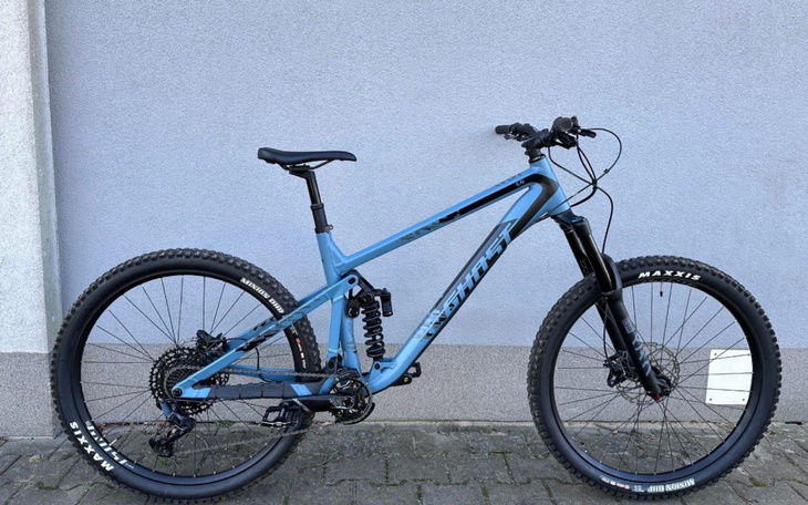 Rower górski w kolorze niebieskim, stojący na tle ściany.