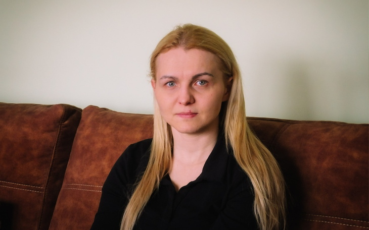 Kobieta siedząca na kanapie, patrząca w kamerę.