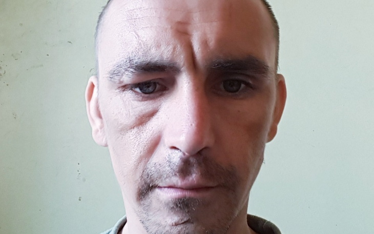 Mężczyzna z poważnym wyrazem twarzy na neutralnym tle.