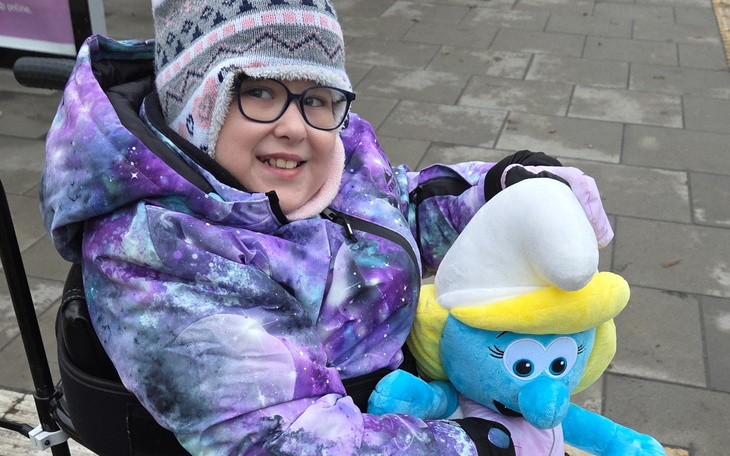 Dziewczynka w wózku z pluszowym stworkiem.