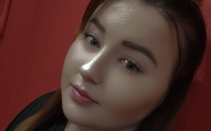 Portret kobiety z delikatnym makijażem na czerwonym tle.