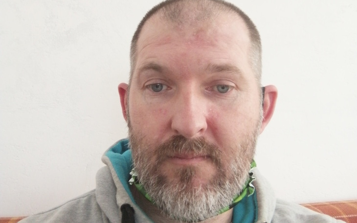 Mężczyzna z brodą, patrzący w kamerę.